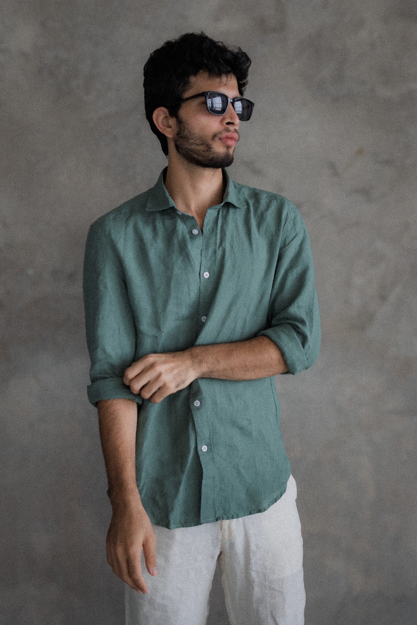Man wearing a green shirt and sunglasses against a gray background