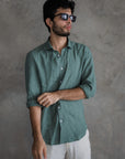 Man wearing a green shirt and sunglasses against a gray background